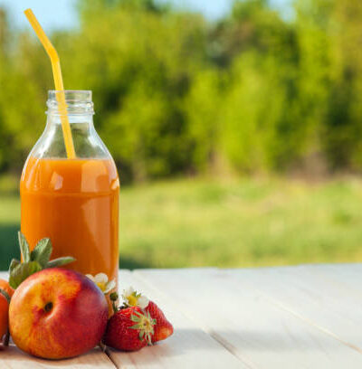 Glass of detox smoothie and fruit on wooden table in the garden
