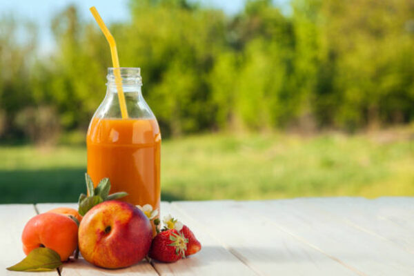 Glass of detox smoothie and fruit on wooden table in the garden