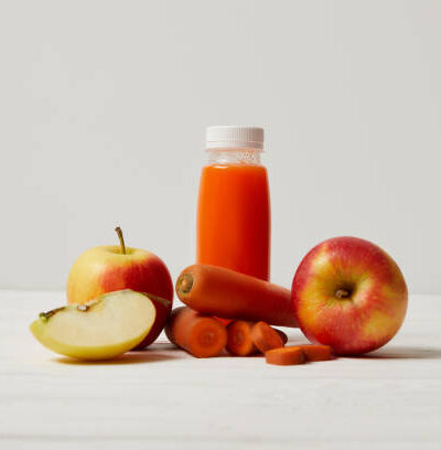 Detox smoothie with apples and carrots on white wooden surface
