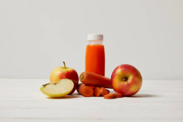Detox smoothie with apples and carrots on white wooden surface